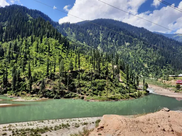 Kaşmir 'deki Neelum Vadisi' nin göz kamaştırıcı gündüz manzarası. Kaşmir 'deki Neelum Vadisi nefes kesici bir yerdir. Bereketli yeşil manzarası, uzun ağaçları ve canlı yeşilliği cennete benzer bir manzara yaratır..