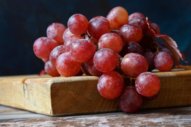 Koyu arkaplanda bir demet pembe üzüm. 