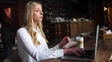 Kafede öğle yemeği sırasında laptopunu kullanıp kahve içen zeki, genç bir iş kadını. Bayan girişimci ya da yönetici uzaktan kumandalı internet üzerinden webinarları izliyor.
