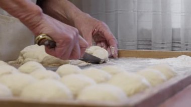 Profesyonel bir mutfakta kıdemli kadın elleri donut yapmak için un hamuru hazırlar. Çiğ hamurun hazırlanması. Ev yapımı donut yapıyorum. Yakın plan. Yüksek kalite 4k görüntü