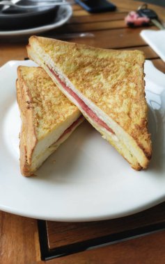 Tütsülenmiş sığır eti ve erimiş peynirle dolu sandviç. İki parçaya bölünmüş.