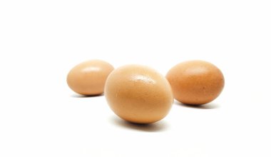 Beyaz arka planda üç çiğ tavuk yumurtası.