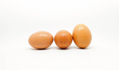 Beyaz arka planda üç çiğ tavuk yumurtası.