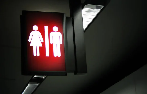 Dark tone public restrooms backlit sign with blurred background.