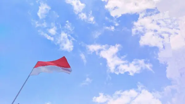 当印度尼西亚国旗在风中飘扬时 蓝蓝的水晶般的天空作为背景 — 图库照片