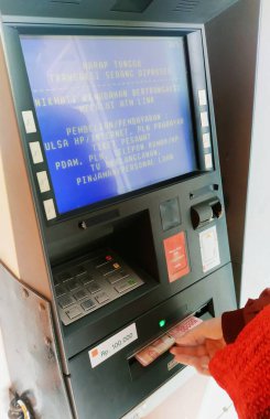 Bandung, Endonezya - 19 Eylül 2023; Kırmızı ceketli bir kadının eli ATM makinesinden çıkan yüz bin rupia 'yı aldı