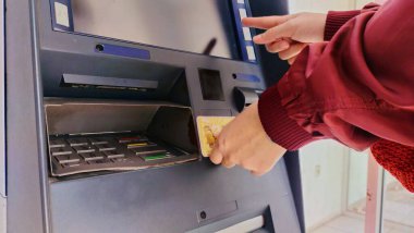 Bandung, Endonezya - 19 Eylül 2023; Kırmızı ceket giyen bir kişinin elinde ATM makinesinin tepesinde bir elektronik geçiş kartı var