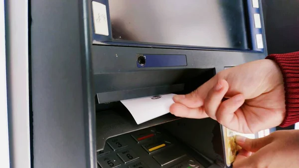 Bandung, Endonezya - 19 Eylül 2023; Bandung, Endonezya - Bir kişinin eli ATM makinesinde başarılı bir şekilde bir e-geçiş ücreti doldurduktan sonra bir kağıt makbuz alır