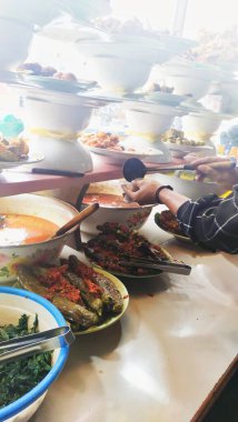 Nasi Padang satıcısı yemek menülerinden birini bir Padang restoranında plastik ambalajla paketliyor.