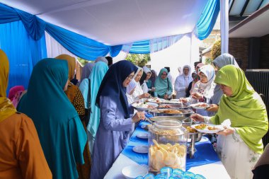 Bandung, Endonezya - 20 Temmuz 2019: Bir grup Shar 'i Müslüman kadın sırayla açık büfe yemekleri yiyor.