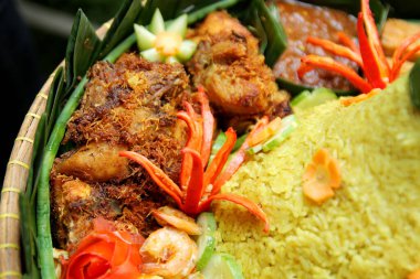 Nasi Tumpeng mezeleri, kızarmış tavuk, kızarmış karides ve sambal gibi.