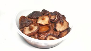 Beyaz arka plandaki bir konteynırda bir yığın şitake mantarı.