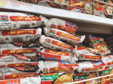 Bandung, Indonesia - March 27th 2024; Stacks of packages of Indomie Mie Goreng (fried noodles) instant noodles are arranged on the shelves of a grocery store or supermarket clipart