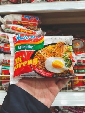 Bandung, Indonesia - March 27th 2024; A person's hand holds a Indomie Mie Goreng (fried noodles) instant noodle clipart