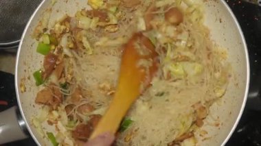 ... üzerinde sosis ve lahana dilimleri olan ev yapımı vermicelli pişirme işlemi sırasında görüldü.