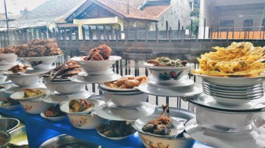 Padang pirinç tezgahlarının çeşitli menüleri camın arkasında sergileniyor. Bunlar sığır eti rendang, ızgara tavuk, karides kırıntıları, omlet ve benzeri şeyler.