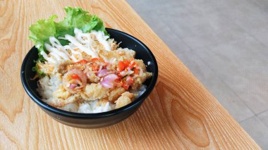 Tavuklu pilav kasesi ve sambal mata. Tahta masada çok cazip duruyor.