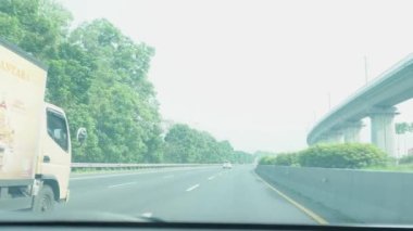 Bandung, Endonezya - 8 Mayıs 2024; sürücü koltuğundan görüş, gün ışığında araba sürmek ve araçlarla çok meşgul olmayan bir çevre yolu durumu