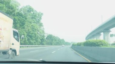 Bandung, Endonezya - 8 Mayıs 2024; sürücü koltuğundan görüş, gün ışığında araba sürmek ve araçlarla çok meşgul olmayan bir çevre yolu durumu