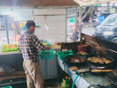 Cianjur, Endonezya - 8 Mayıs 2024; Kızarmış tavuk satıcısı müşterinin siparişini pişirmekle meşgul.