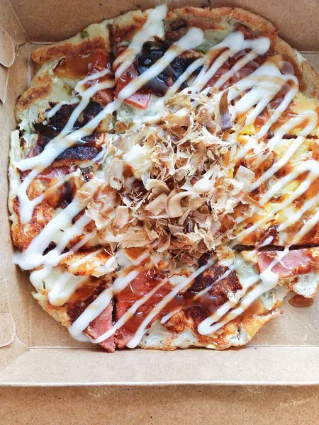 Tipik Japon sokak atıştırmalıkları, ambalaj kutusunda Okonomiyaki. Okonomiyaki sebze, et, balık vs. içeren buğday unundan yapılır. Sonra demir bir tabakta pişirildi ve üzerine sos sürüldü.