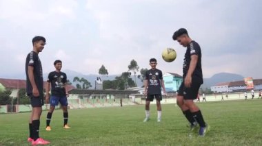 Bandung, Endonezya - Ekim 2023; oyuncular amatör futbol takımları arasındaki dostluk maçı öncesinde ısınırken topu paylaşma alıştırması yapıyorlar