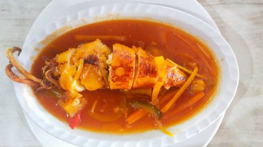 Beyaz bir tabakta Cumi Asam Manis (tatlı ve ekşi mürekkep balığı)