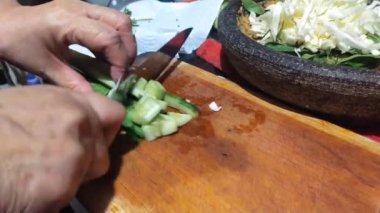 Lotek 'in yemek malzemelerinden biri olarak salatalık kesmek. Lotek, fıstık soslu (Endonezya) sebzelerden yapılan bir salatadır.