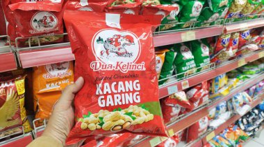 Bandung, Endonezya - 1 Ağustos 2024; Bir süpermarkette Dua Kelinci markalı kavrulmuş fıstık tutan bir kişi
