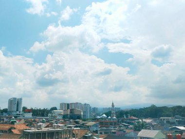 Gün boyunca mavi gökyüzünün altındaki binaların ve evlerin yoğunluğunun portresi.