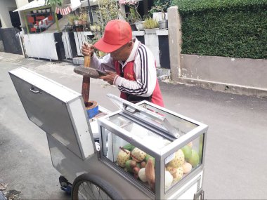 Bandung, Endonezya - 17 Ağustos 2024; Rujak Tumbuk (ezilmiş rujak) satıcı, Rujak baharatıyla serpiştirilmiş çeşitli meyve parçalarından oluşan bir aperatif