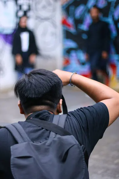 Bandung, Endonezya - 11 Ocak 2020; Grafiti arka planında bir çiftle düğün öncesi fotoğraf çeken bir fotoğrafçı