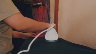 Ev hanımı, sabahları ütü kullanarak çamaşırları ütülüyor.