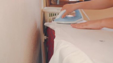 Ev hanımı, sabahları ütü kullanarak çamaşırları ütülüyor.