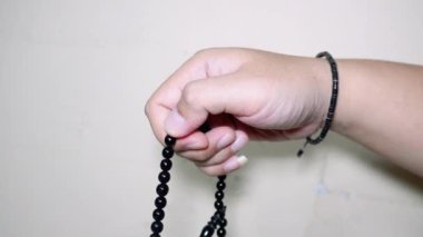 Beyaz arkaplanda izole edilmiş, boş kopya alanı olan Tasbih için siyah tespih ya da tasbih tutan Müslüman el