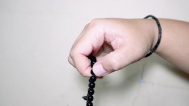 Beyaz arkaplanda izole edilmiş, boş kopya alanı olan Tasbih için siyah tespih ya da tasbih tutan Müslüman el