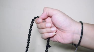Beyaz arkaplanda izole edilmiş, boş kopya alanı olan Tasbih için siyah tespih ya da tasbih tutan Müslüman el