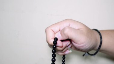 Beyaz arkaplanda izole edilmiş, boş kopya alanı olan Tasbih için siyah tespih ya da tasbih tutan Müslüman el