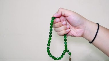 Beyaz arkaplanda izole edilmiş boş fotokopi alanı olan Tasbih için yeşil taştan tespih tutan Müslüman el.