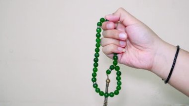 Beyaz arkaplanda izole edilmiş boş fotokopi alanı olan Tasbih için yeşil taştan tespih tutan Müslüman el.