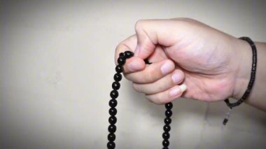 Beyaz arkaplanda izole edilmiş, boş kopya alanı olan Tasbih için siyah tespih ya da tasbih tutan Müslüman el