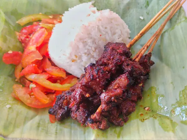Sokak yemeği, keçi sambal ve muz yapraklı beyaz pirinç ile servis edilen satay.