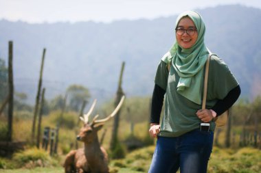 Ranca 'da poz veren güzel Müslüman kadın Ciwidey' in arka planında bir geyik olan geyik üreme bölgesinde