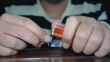 Düşük ışık odasında sigara içen bir adamın yakın çekimi.