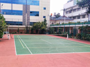 tennis courts between office buildings or apartments as one of the sports facilities offered clipart