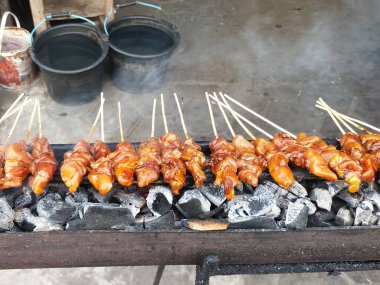 Sıcak kömür ve mangal kömürlerinin üzerinde kızartılıp satay tezgahında et pişirilip dumanlanana kadar satürlerin sıraları kızartılıyor.