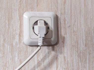 Duvara beyaz elektrik prizi takılı beyaz priz
