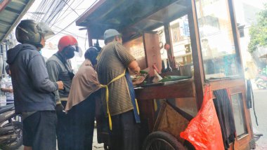 Bandung, Endonezya - 3 Ekim 2024; müşteriler tarafından çevrelenmiş tavuk satay satan adam sipariş verirken