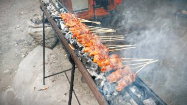 Sıcak kömür ve kömürün üstünde kızartılıp satay tezgahında et pişirilip dumanlanana kadar sıra sıra şişler kızartılıyor.
