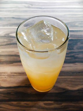 Bir bardak buzlu portakal suyu ahşap masaya izole edilmiş.